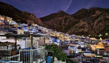 Nighttime view of Chefchaouen illuminated under mountain shadows.