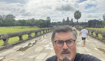 Man posing on a pathway with ancient structures in the background.