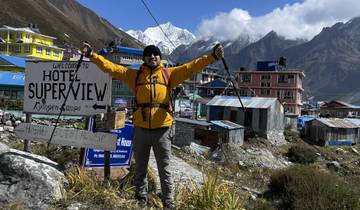 Person with trekking poles celebrating in front of Everest Base Camp sign.
