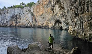 Man standing by a scenic rock coastline.