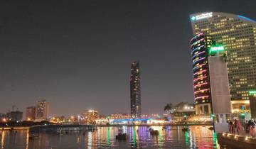 City skyline with colorful lights reflecting on water at night.