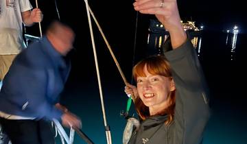 People fishing off the side of a boat at night.