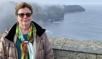 Woman standing with misty Cliffs of Moher in the background.