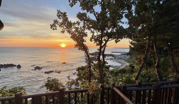 Sunset over the ocean with rocky shoreline.