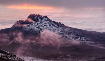 Mountain peak surrounded by clouds at sunset.