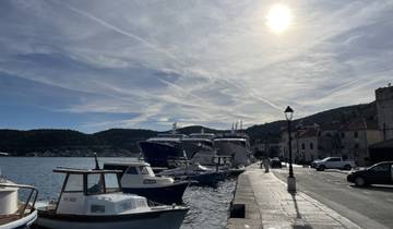 Several boats docked at a pier under a bright sunlit sky.