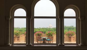 Table with chairs on a terrace overlooking the Taj Mahal.