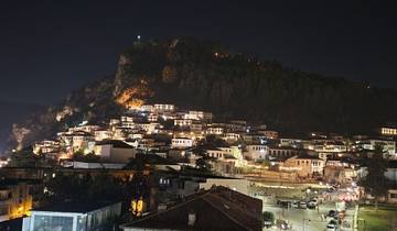 Night view of a town built on a hillside with bright lights.