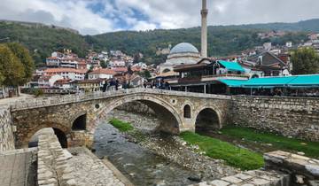 Stone bridge over a creek in a historic town area.