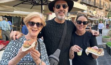 Three people enjoying street food in a market.