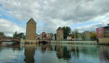 Historic buildings by a river under a cloudy sky.