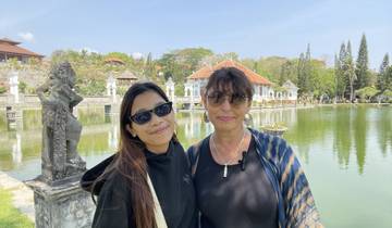 Two people posing by a serene pond with traditional Balinese architecture.