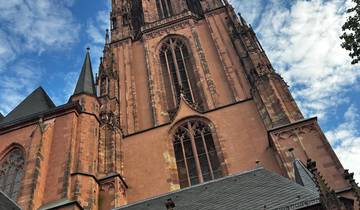 A close-up view of a tall gothic church tower against a blue sky.