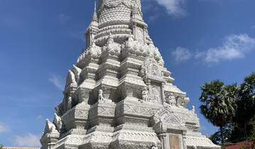 White stone pagoda with intricate carvings against a blue sky.