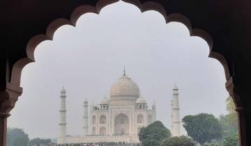 Taj Mahal viewed through an ornate archway on a hazy day.