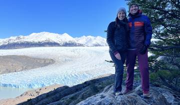 Couple standing in front of a vast glacier with snowy mountains.