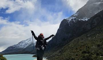 Hiker posing with trekking poles in front of snow-capped mountains.