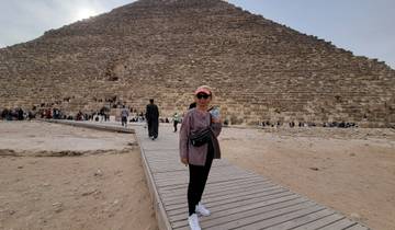 Woman posing in front of a pyramid with many visitors.