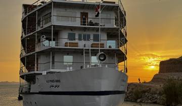 A large cruise ship at sunset on a river.