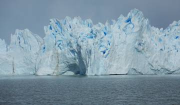 Expansive glacier with blue ice and water in the foreground.