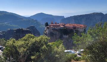 Monastery perched on a rocky outcrop with a mountainous background.
