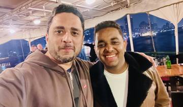 Two people smiling on a night boat cruise.