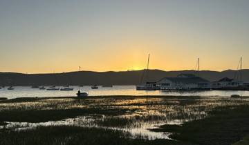 Sunset over a harbor with boats and calm waters.