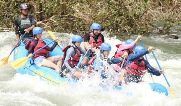 Excited group rafting down rapids in helmets and life jackets.