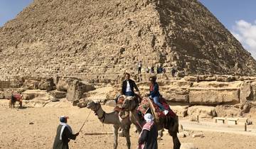 Two people riding camels near the Great Pyramid of Giza.