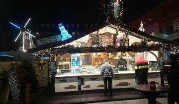 Outdoor market with illuminated stalls and people browsing.