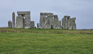 Stonehenge in an open field under a cloudy sky.