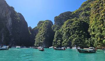 Boats and tourists in turquoise waters surrounded by limestone cliffs.