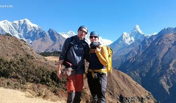 Two hikers posing with mountain peaks in the background.