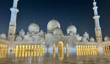 Illuminated mosque with reflection in water.
