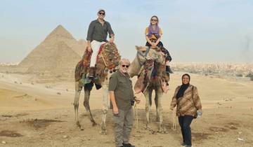 Group with camels in front of pyramids.