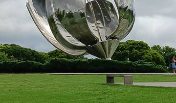 Close-up of a reflective metal sculpture in a park setting.
