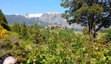 Mountains with snow caps and green foreground, a group of tourists visible.