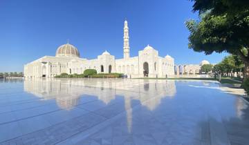 Beautiful mosque with a tall minaret reflected on polished ground.