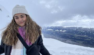 Woman smiling in a snowy mountain landscape.