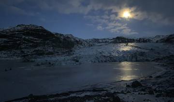 Nighttime view of a glacier under a bright moon.
