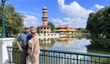 A couple posing in front of a scenic building and water reflection.