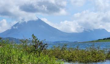 Volcano in the distance with a lake and vegetation.