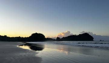 Calm beach at sunset with waves lapping against the shore.