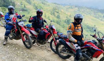 Three motorcyclists posing on a dirt trail with terraced fields.