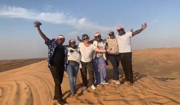 Group of people joyfully posing on a desert dune.