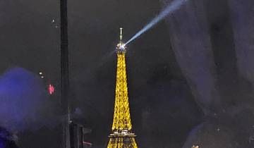 The Eiffel Tower illuminated at night with a beam of light.