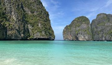 Scenic beach view with towering cliffs and turquoise water.