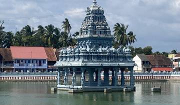 Ornate temple structure surrounded by a water body in a picturesque setting.