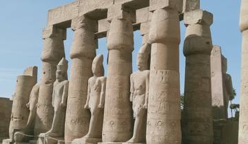 Columns and statues in ancient ruins against a blue sky.