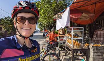 Person smiling near a street food stall with bicycles in the background.